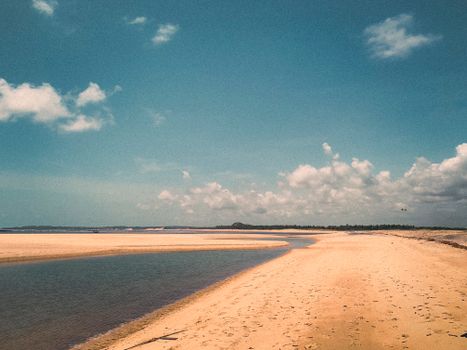 Explore the serene sandy shores and blue skies of Barra do Cunhaú, a picturesque Brazilian beach.