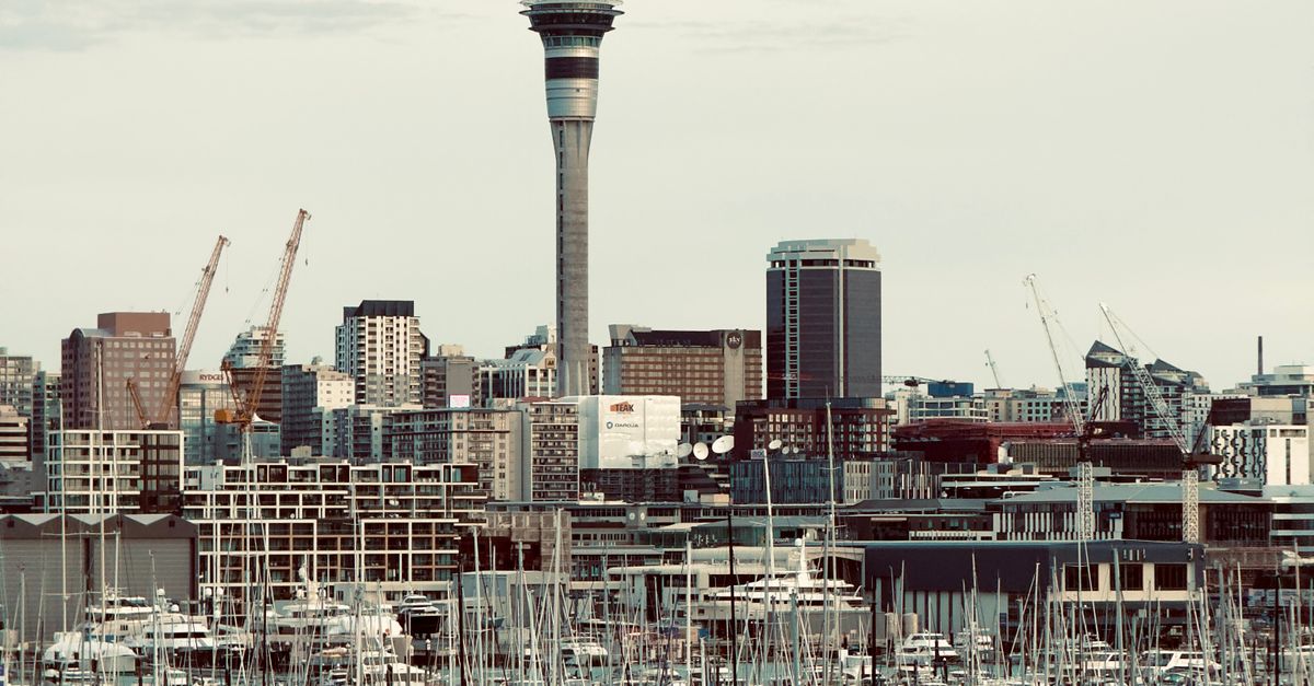 A scenic view of Auckland's iconic Sky Tower with bustling harbor and cityscape.