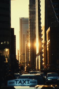 Sunset view of the bustling Toronto cityscape with skyscrapers and a taxi in the foreground.