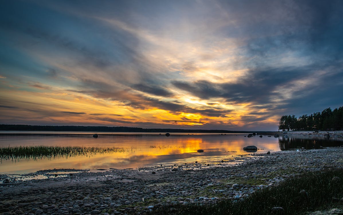 Free Body of Water Under Brown and Blue Sky at Golden Hour Stock Photo