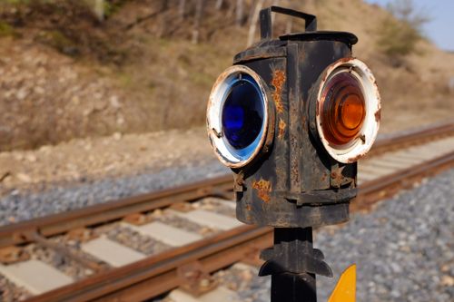 Free Close-up of a vintage railroad signal with blue and amber lenses along train tracks. Stock Photo