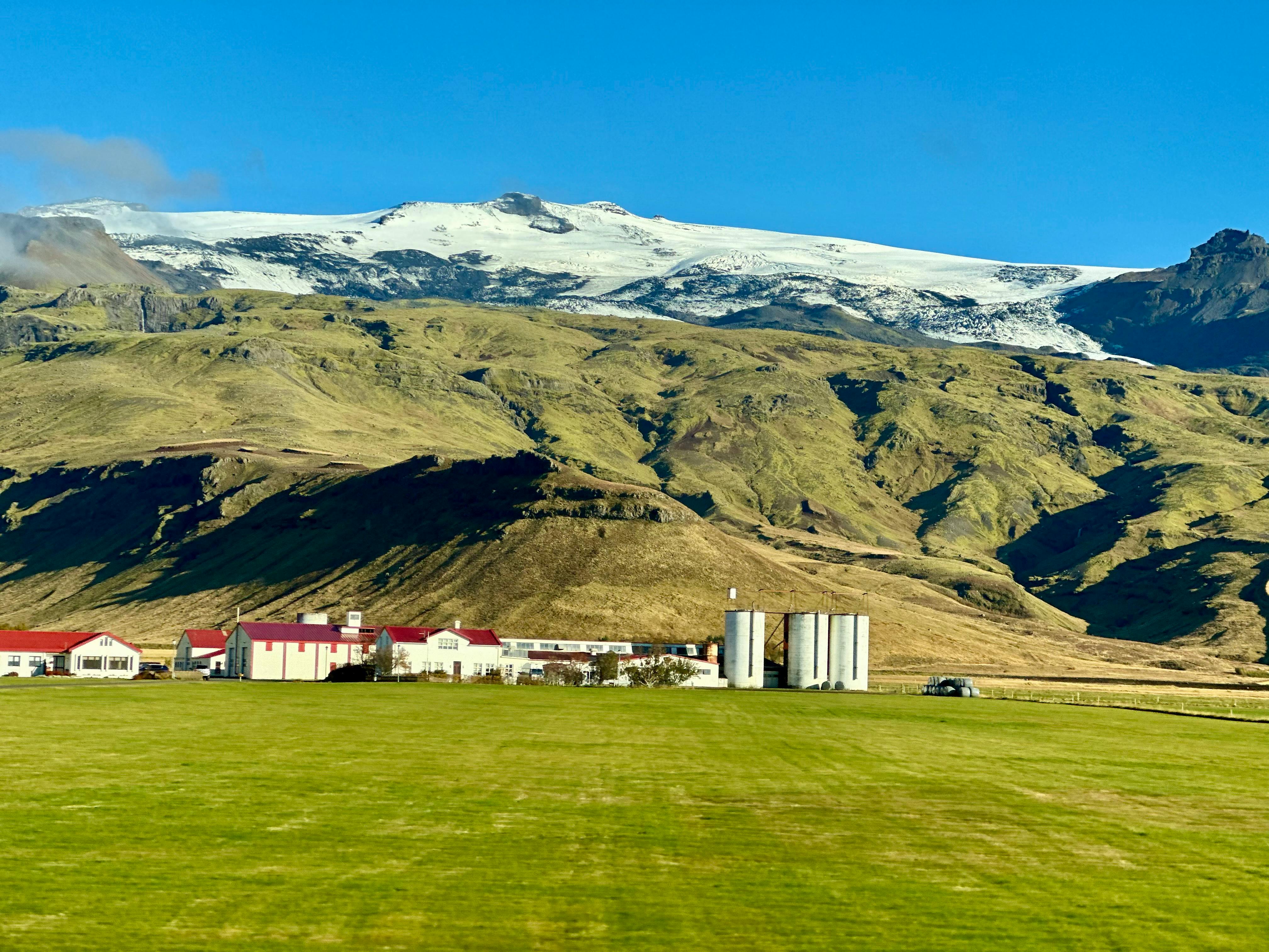 scenic farm landscape beneath icelandic glacier