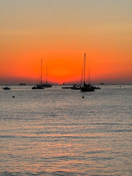 Tranquil scene of sailing boats at sunset over the calm waters of Ibiza, perfect for travel and relaxation themes.