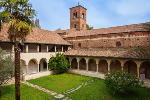 Picturesque Italian courtyard with arches and bell tower under a clear sky.