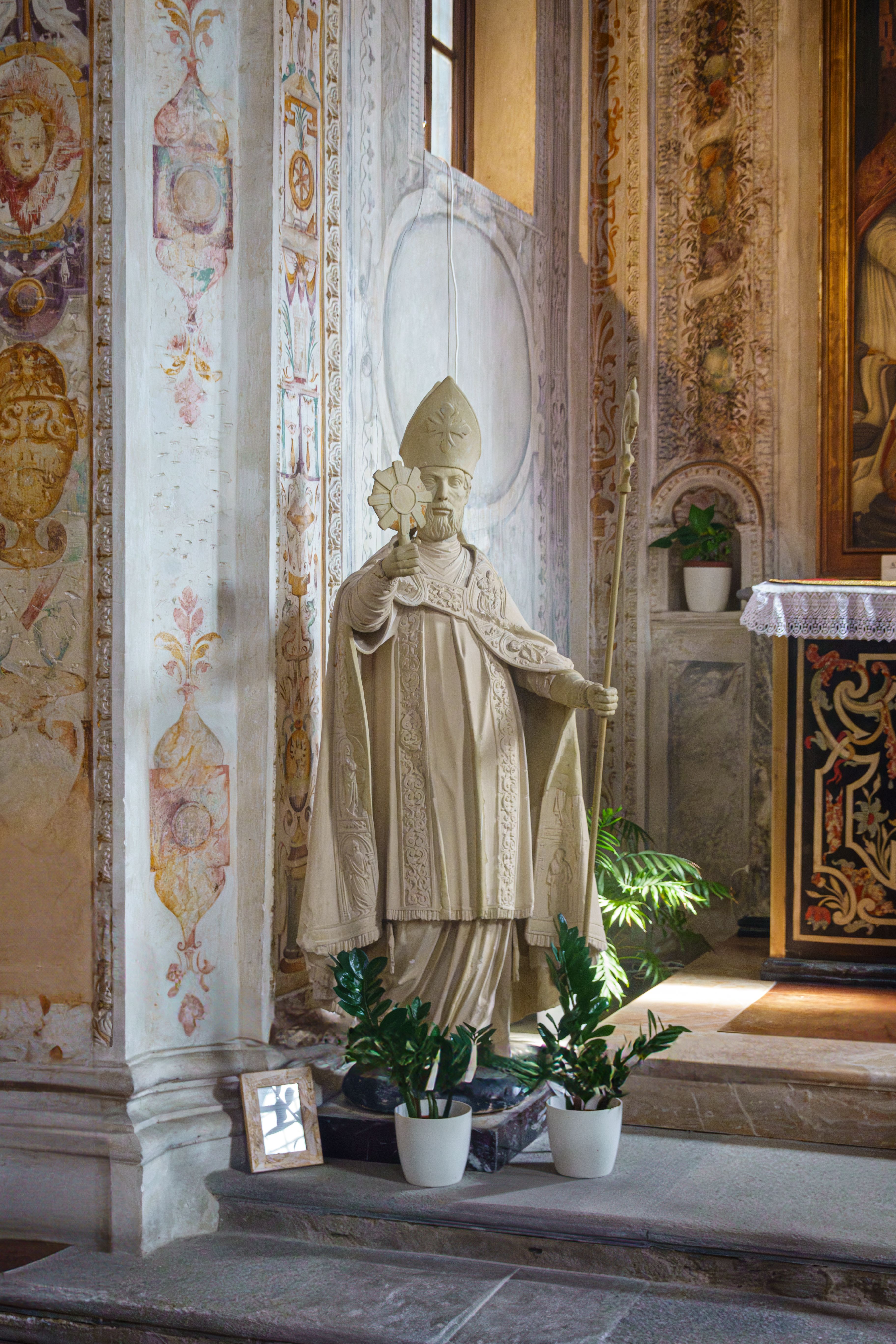 A beautifully lit religious statue inside a historic church, adorned with intricate decorations.