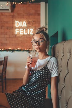 Stylish young woman sipping a beverage in a trendy cafe with warm decor.