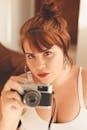 一位红发女子在室内拿着老式相机化眼妆