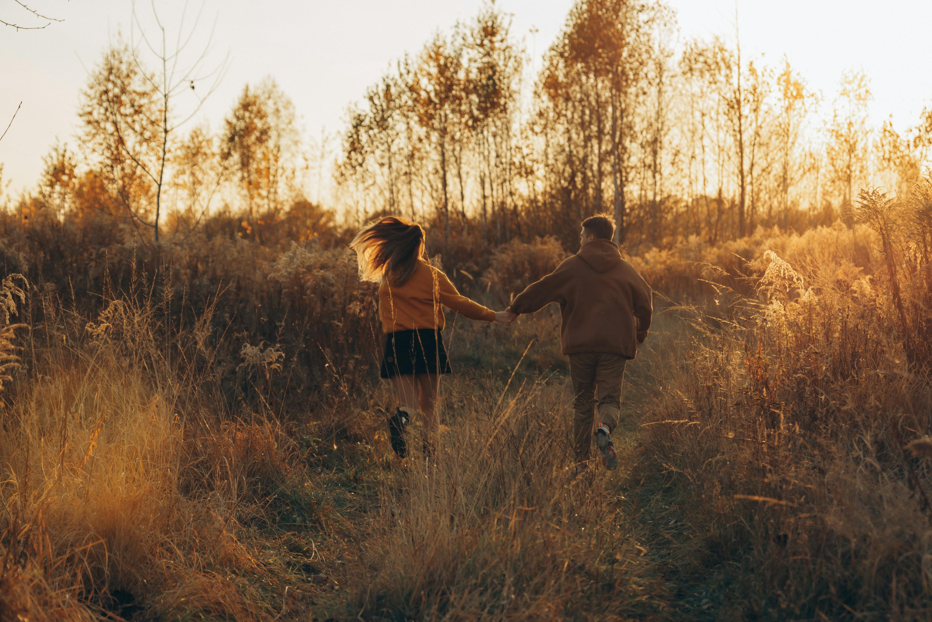 Couple walking hand in hand through golden Ukrainian fields at sunset.