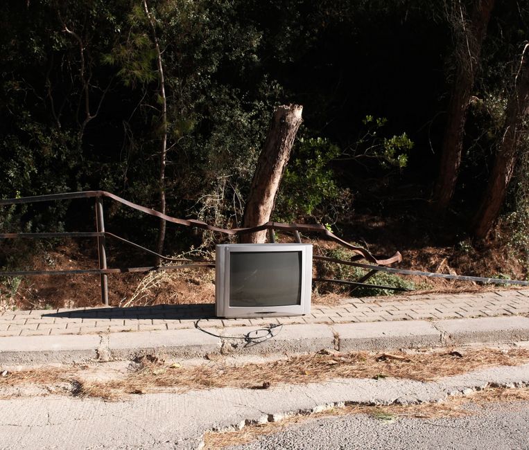 自然に囲まれたイズミールの歩道に放置されたブラウン管テレビ。