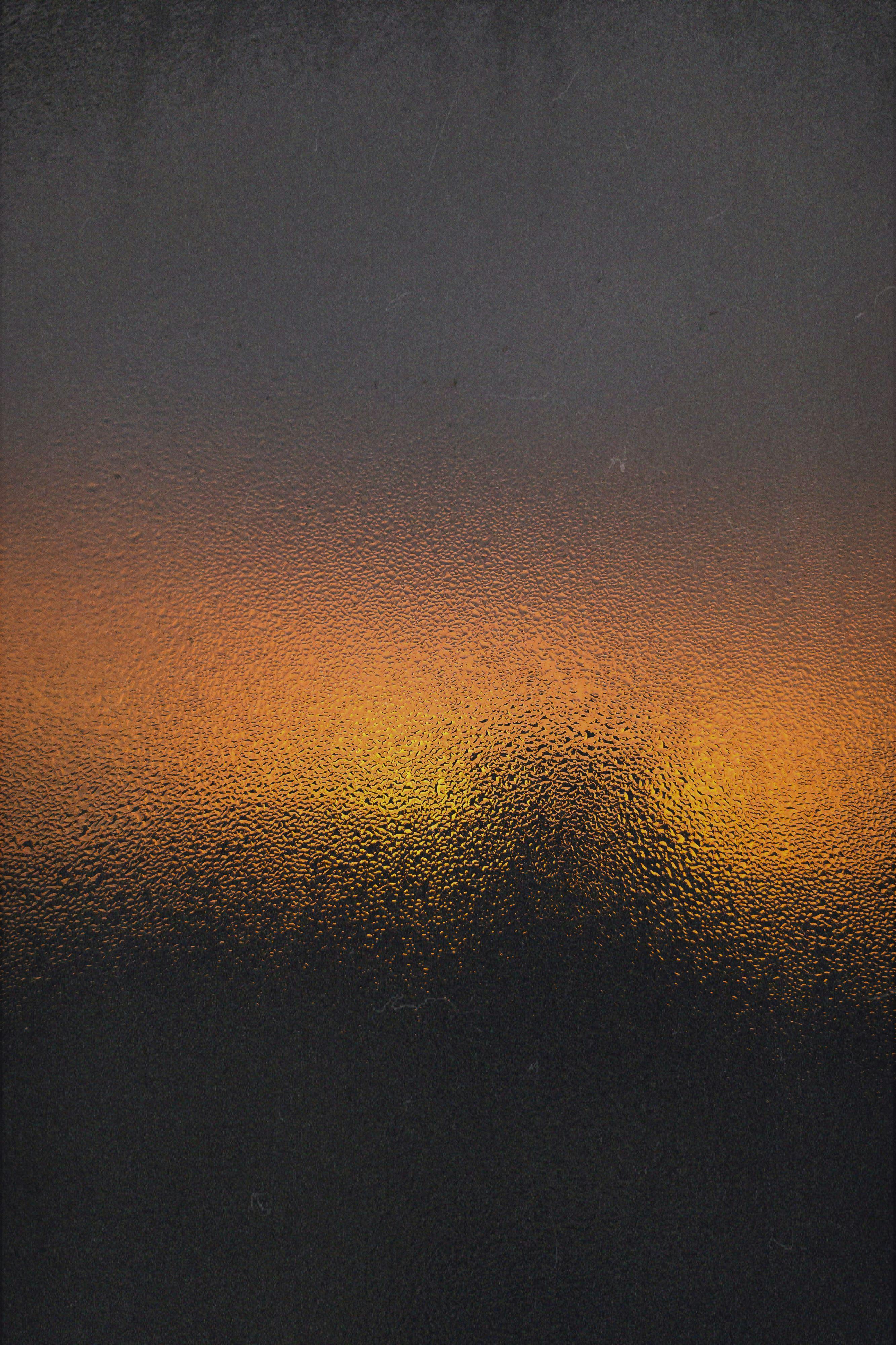 Captivating sunset glow seen through textured glass, offering a warm abstract view.
