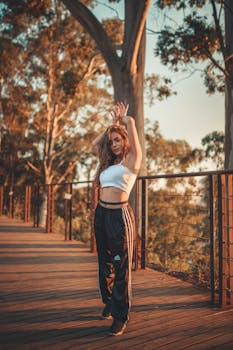 午后阳光下，一位时尚女子在木桥上摆出姿势，展现出自信的举止和现代服装