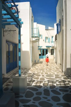 Picturesque white and blue alley in Hua Hin with a solitary figure, enjoying a sunny day.