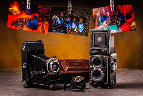 Free Vintage cameras displayed with vibrant photos hanging above. Classic and artistic feel. Stock Photo