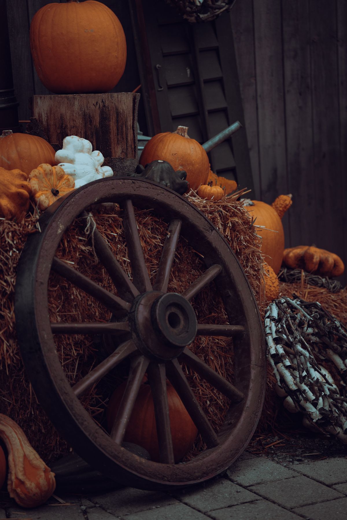 A rustic autumn scene featuring pumpkins, hay, and a vintage wooden wheel, embodying the fall harvest spirit. Stock Photo.