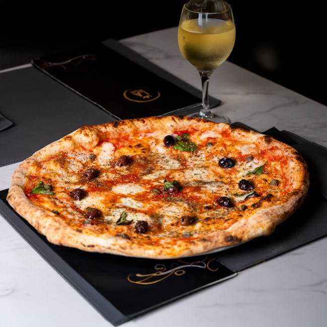 Tasty Neapolitan pizza paired with white wine on elegant table setting.