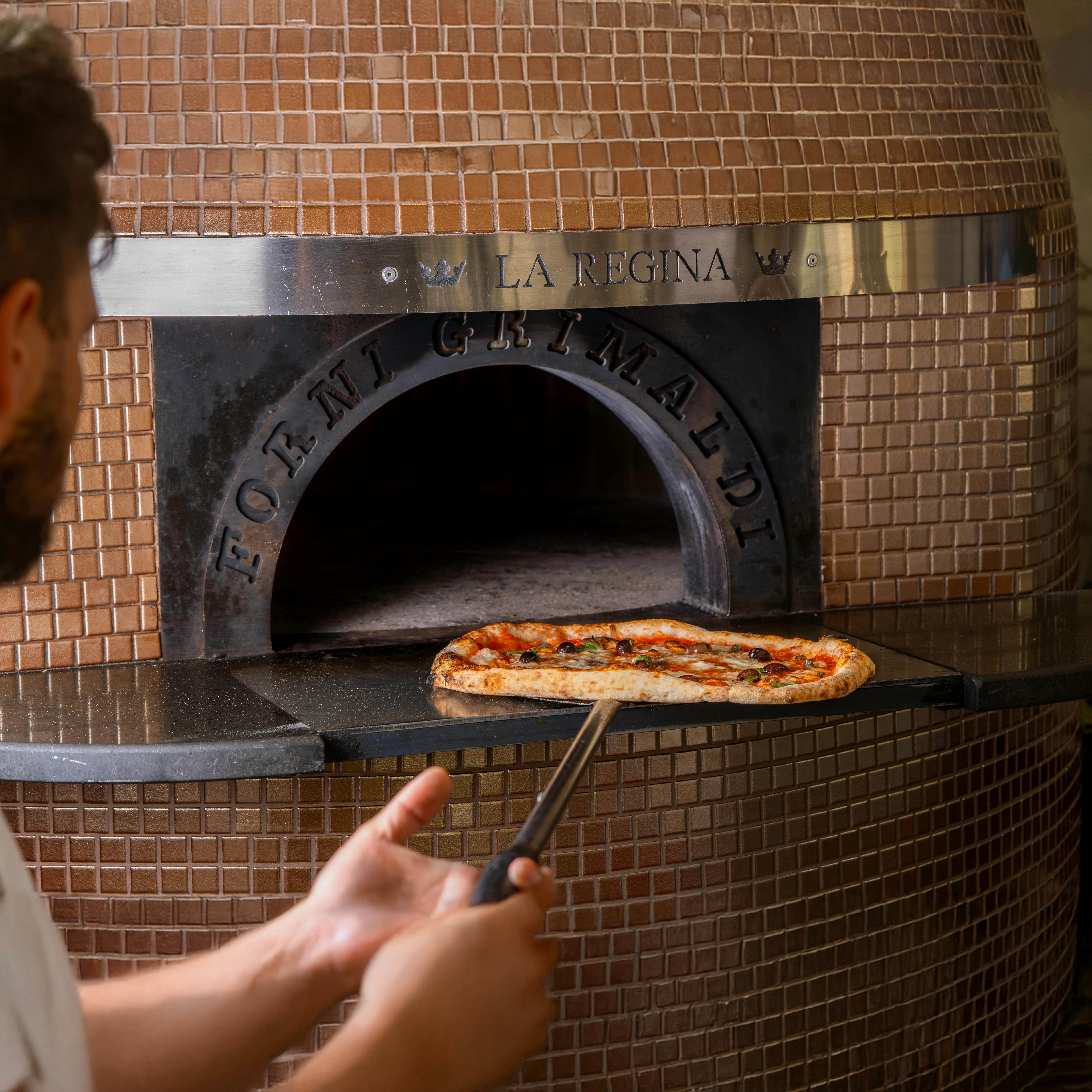 Chef prepares to bake pizza in a traditional brick oven for perfect cooking.