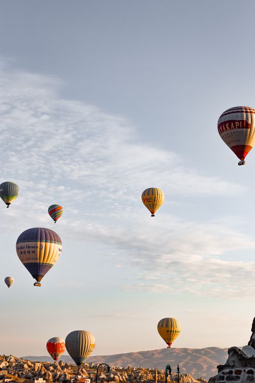 Free A stunning view of colorful hot air balloons floating over the rocky landscape of Cappadocia, Turkey. Stock Photo