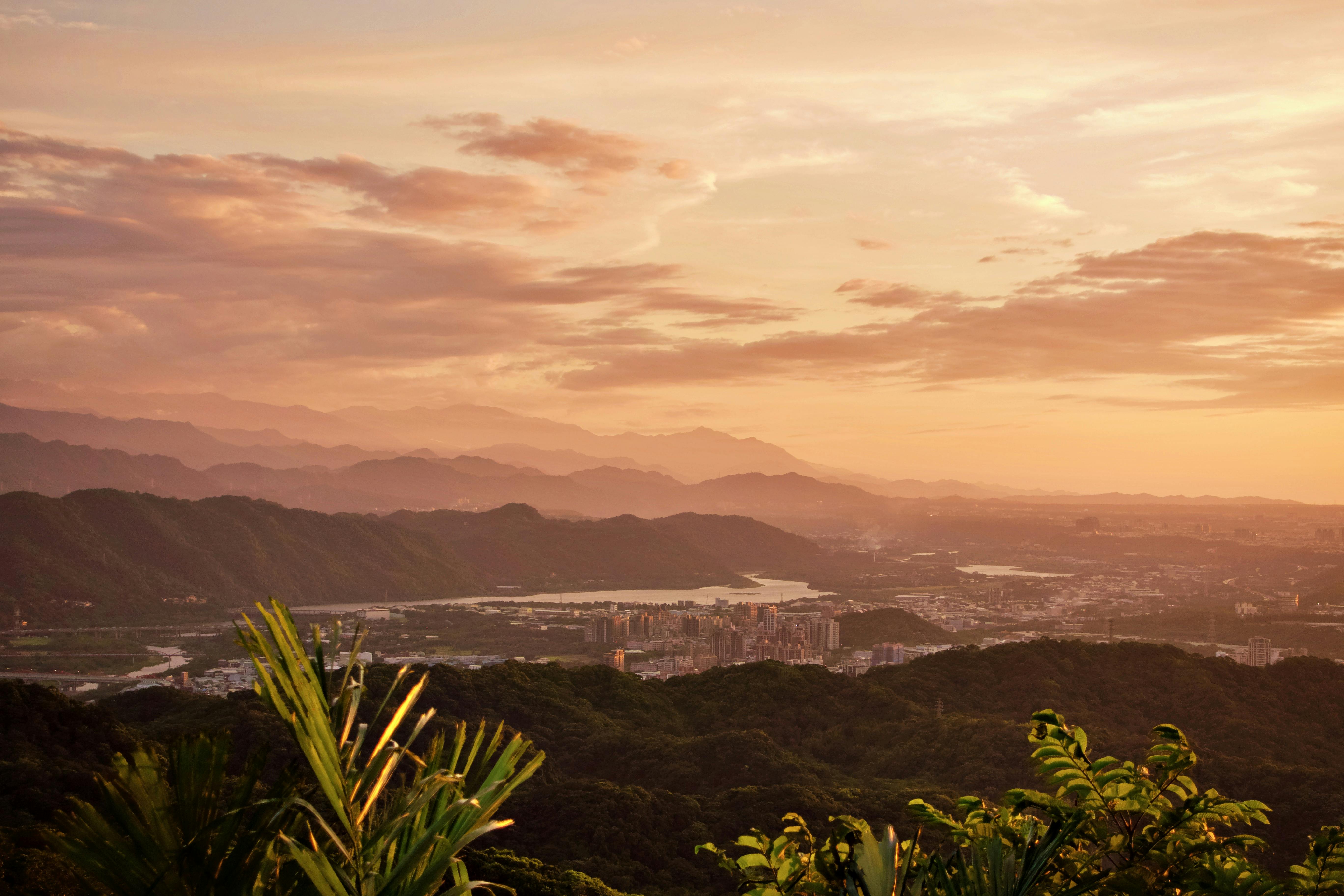 Breathtaking sunset view over Taipei mountains and city skyline with lush greenery.