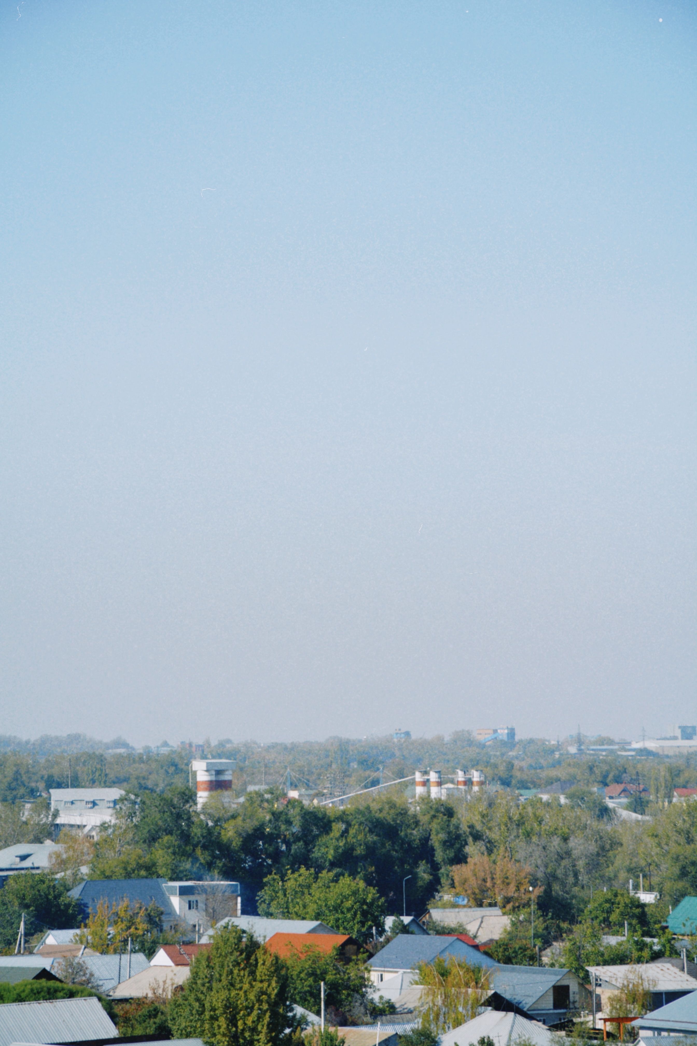 Peaceful view of Almaty suburbs against a clear sky, showcasing distant horizons.