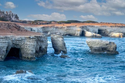 Explore the stunning sea caves and blue waters along the rocky coast of Paphos, Cyprus.