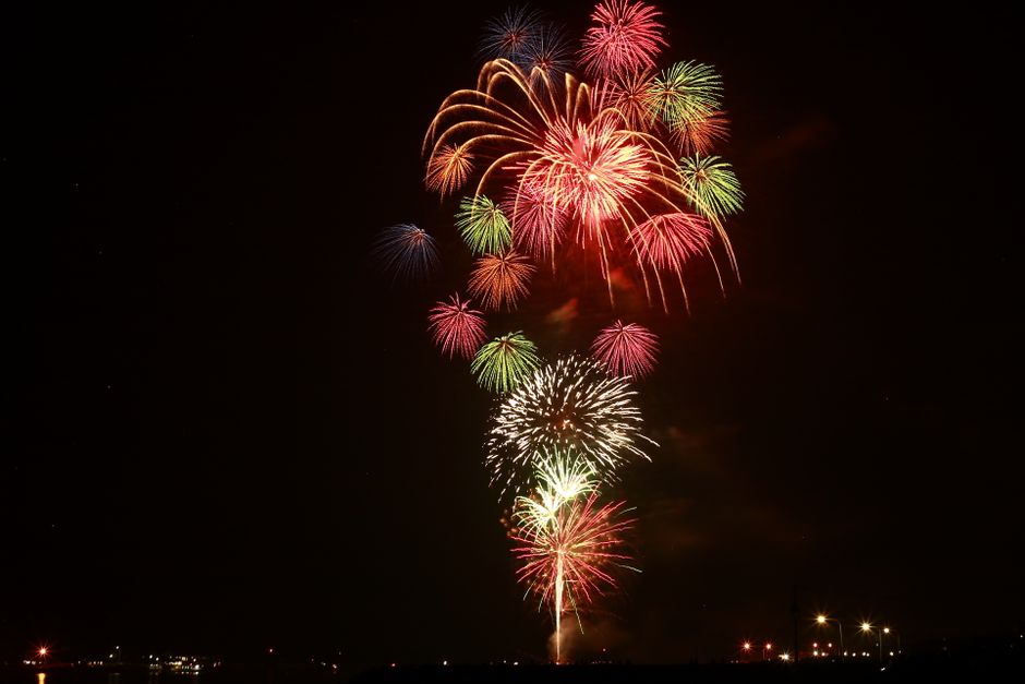 お祝いのイベント中に夜空に色とりどりの花火が弾けています。