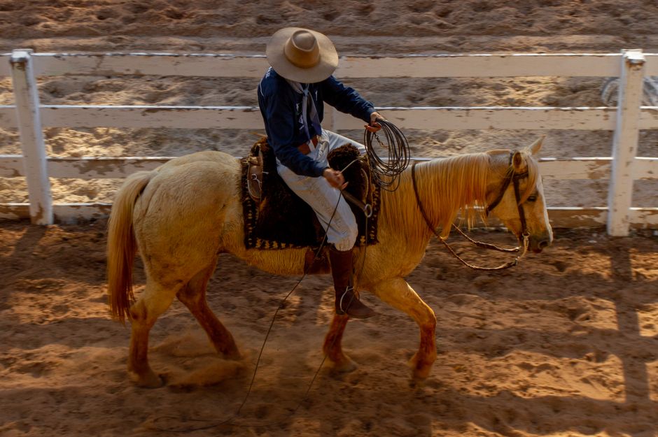 Cowboy riding horse in Brazilian arena, showcasing traditional attire and equestrian skills.