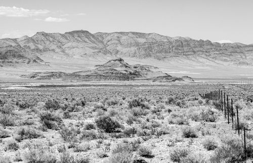 Free A captivating black and white photo of a mountainous desert landscape with rugged terrain and a vast sky. Stock Photo