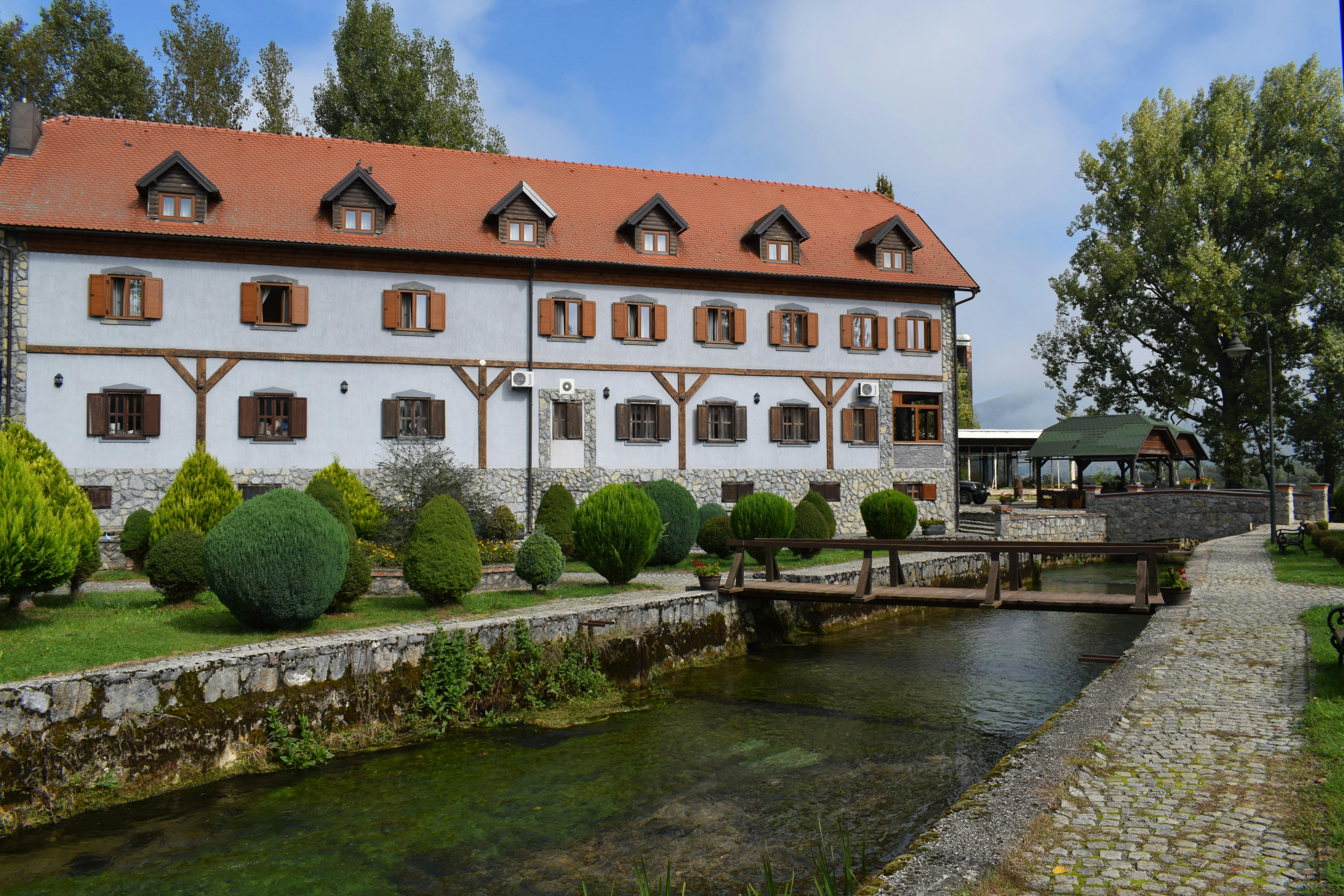Discover a beautiful rustic hotel in Otočac, Croatia, nestled by a serene stream and lush greenery.