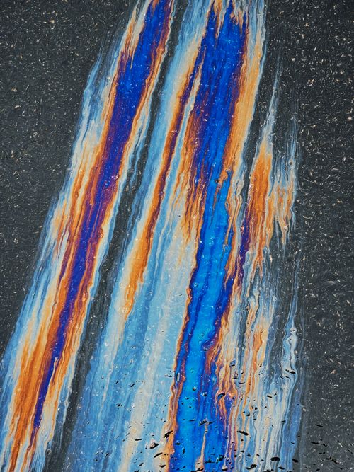 Free Colorful swirls of oil creating abstract patterns on wet asphalt surface. Stock Photo