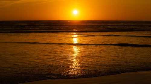Free Capture of a serene sunset with golden reflections over the ocean waves. Stock Photo