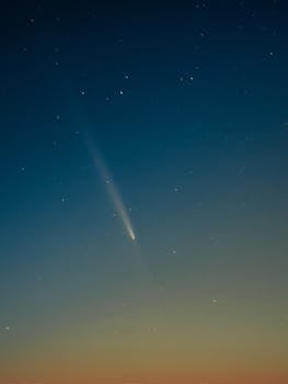 A beautiful comet streaks across a star-filled night sky, offering a mesmerizing celestial view.