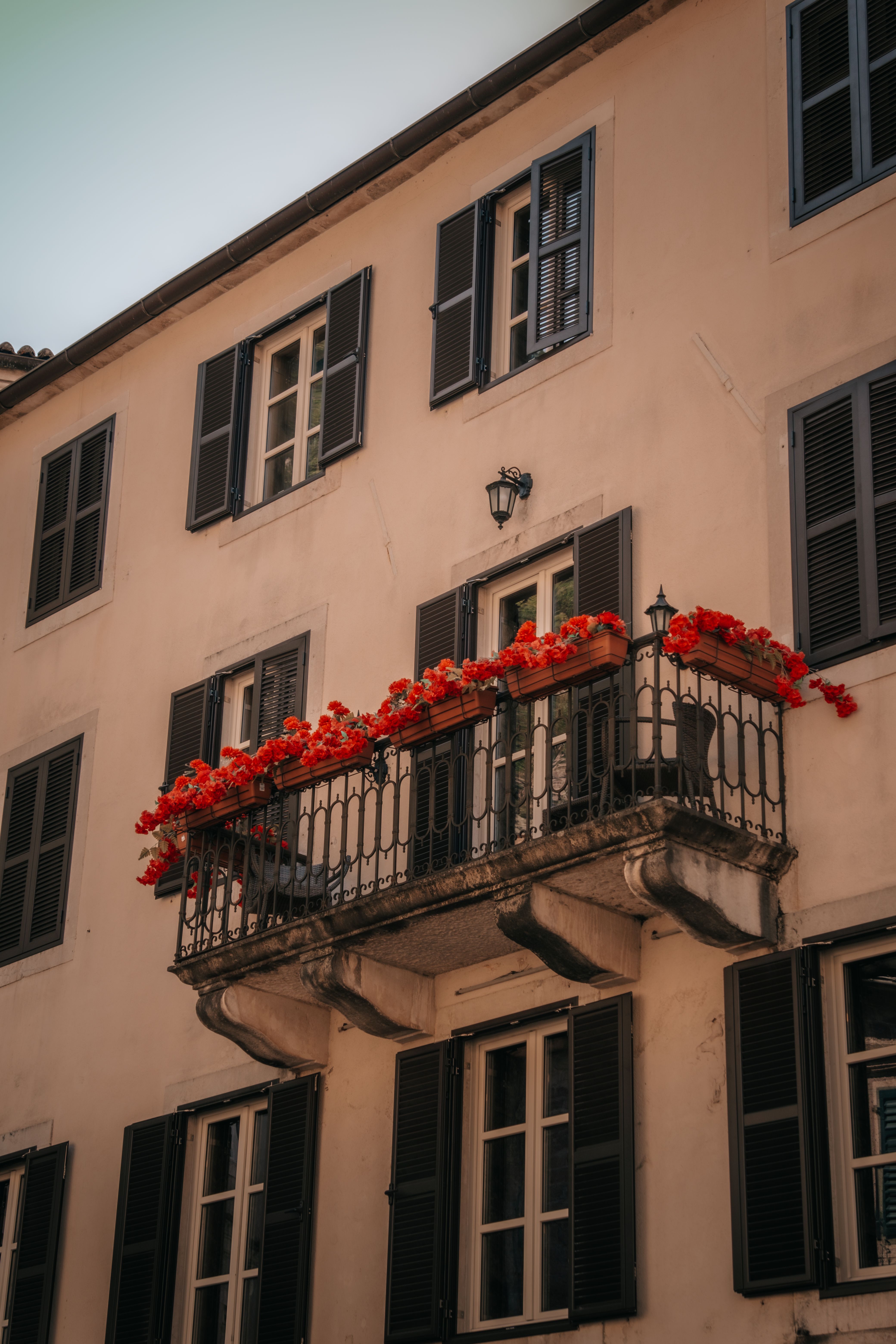 Charming old town balcony with red flowers and wrought iron railing