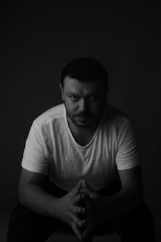 Black and white portrait of a man in a white shirt, seated and looking directly at camera.