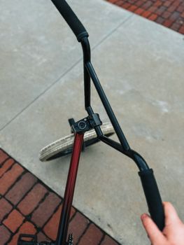 Close-up view of bicycle handlebars and wheel on a paved surface.