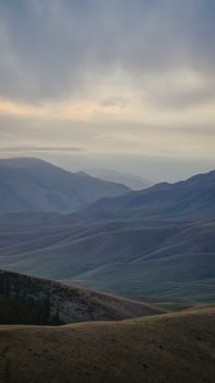 Tranquil view of rolling mountains under a serene sky at dusk, capturing nature's peaceful beauty.