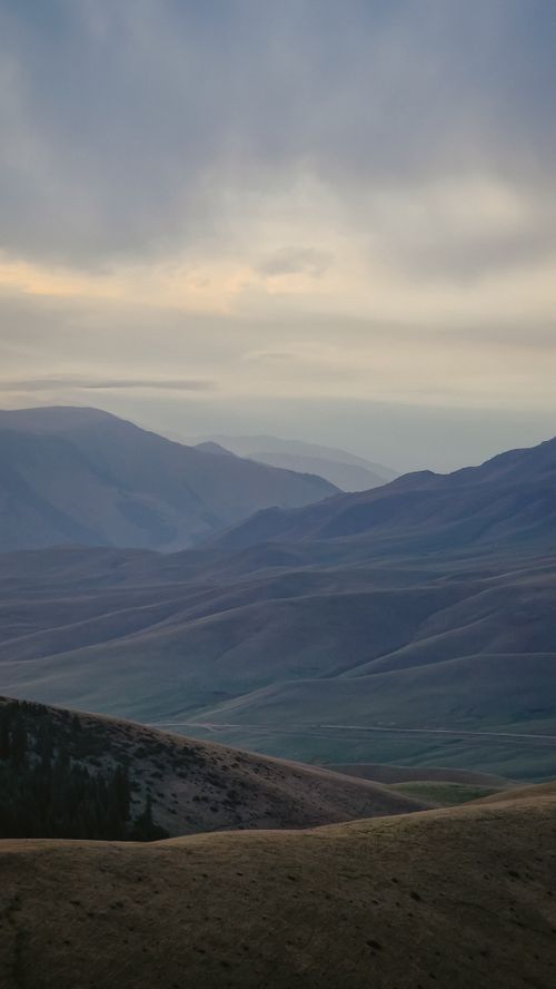Free Tranquil view of rolling mountains under a serene sky at dusk, capturing nature's peaceful beauty. Stock Photo
