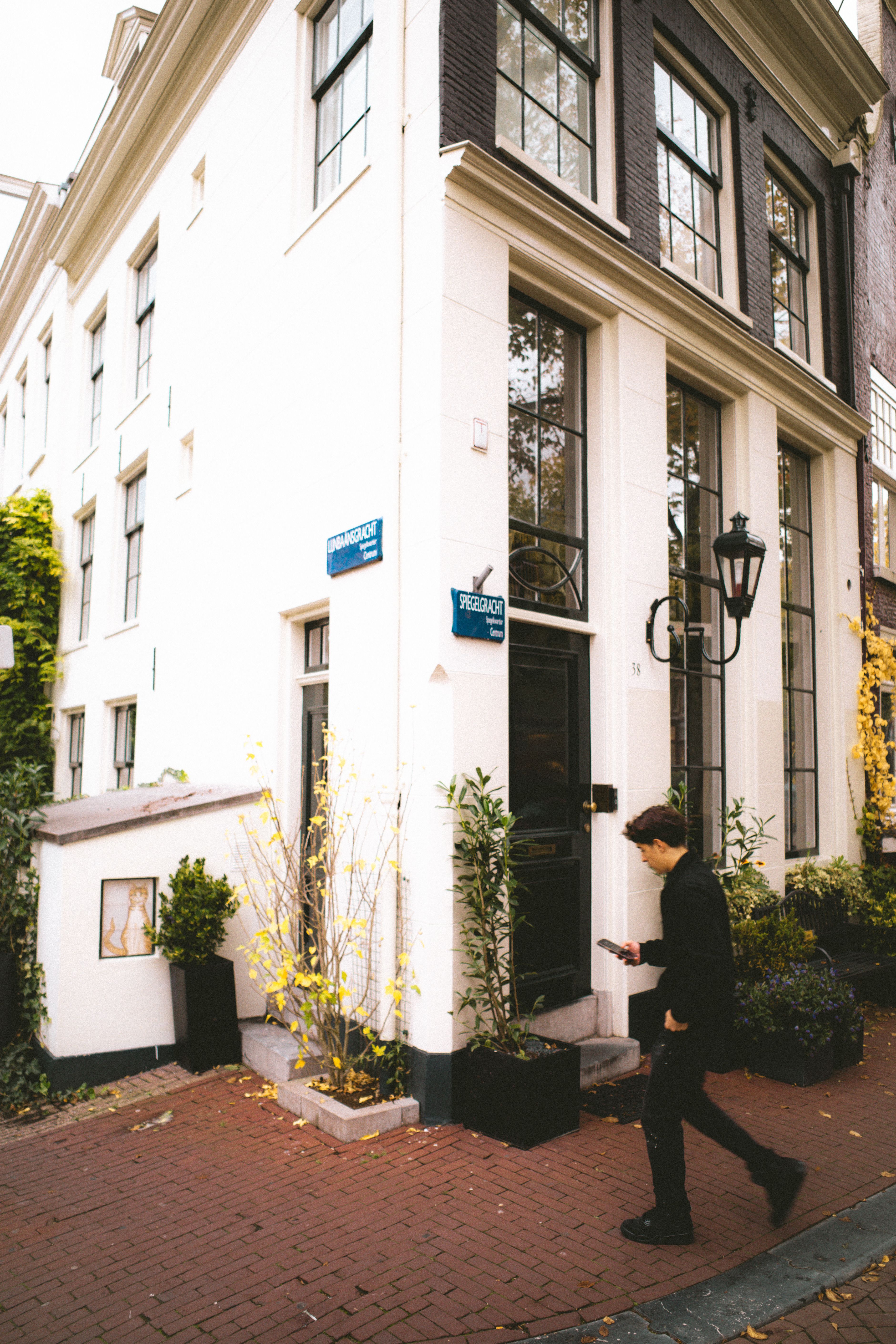 A person walking past classic Amsterdam architecture on a street corner.