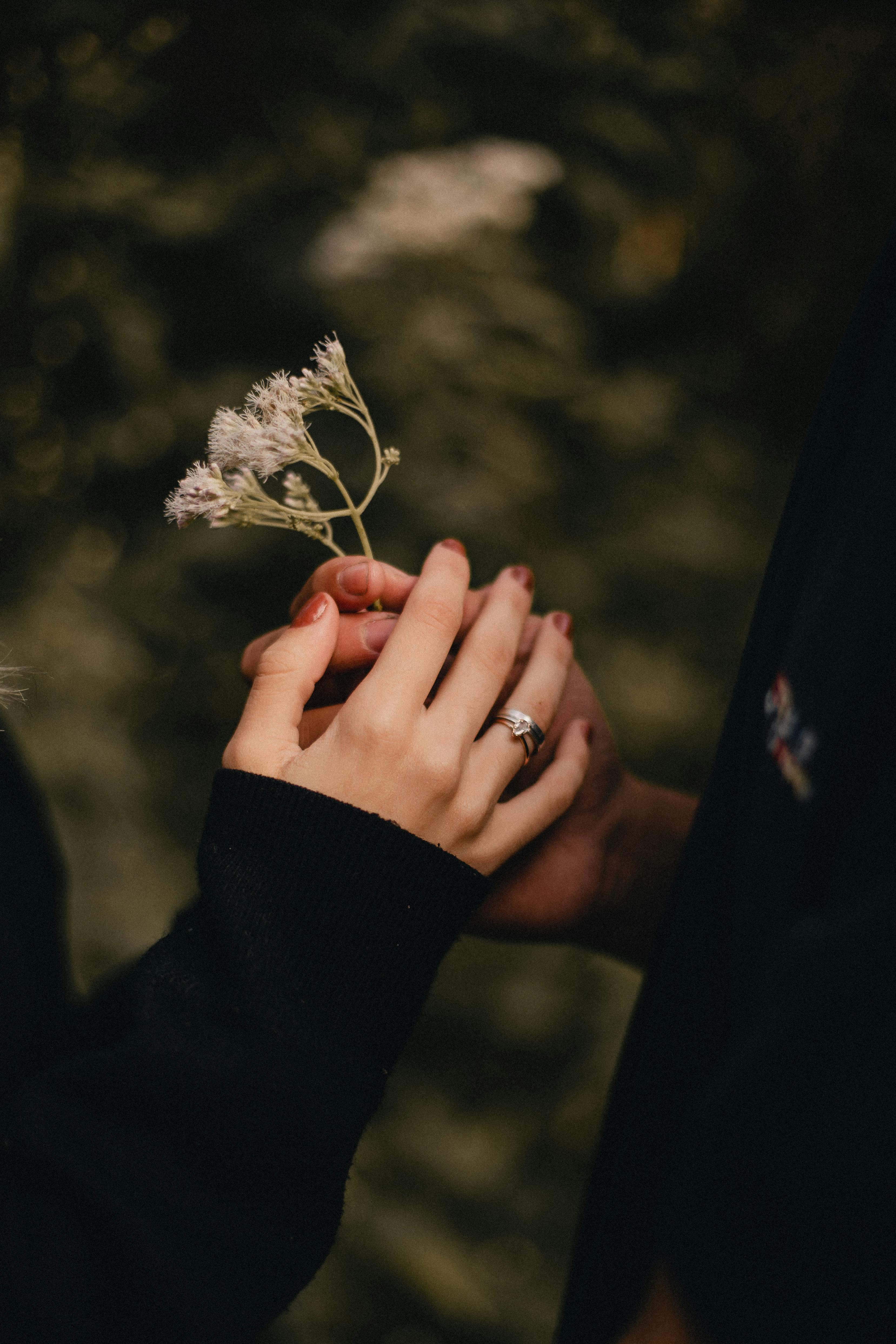 Intimate moment captured with hands holding delicate wildflowers, symbolizing love and connection.