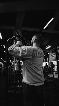 Man exercising in gym, black and white image, focusing on fitness and strength.
