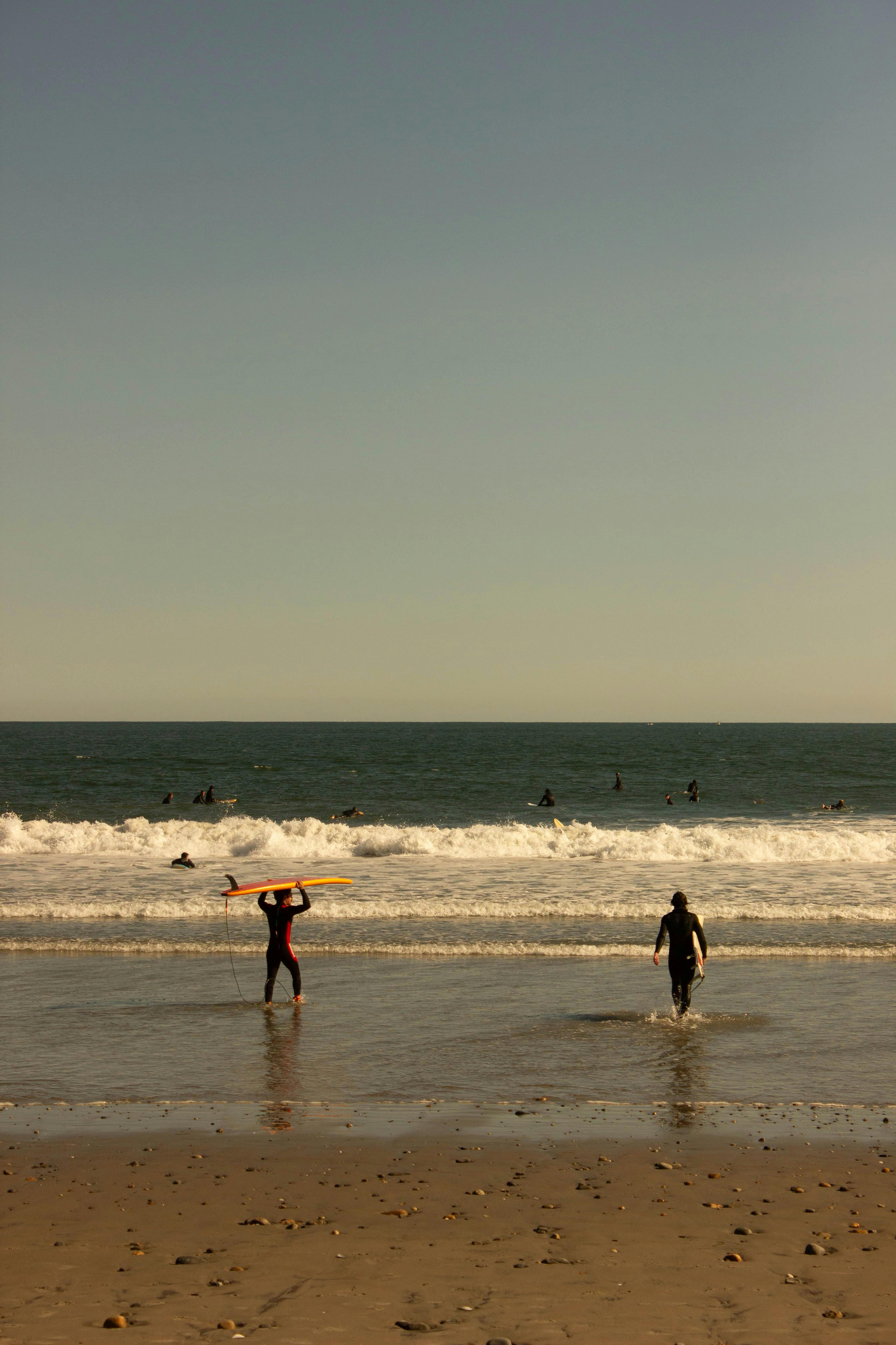 Surfers enjoy the waves at Narragansett Beach, Rhode Island, during a serene sunset.