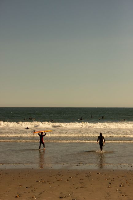 Surfers enjoy the waves at Narragansett Beach, Rhode Island, during a serene sunset.