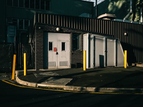 Exterior view of an industrial building with metal doors and bollards.