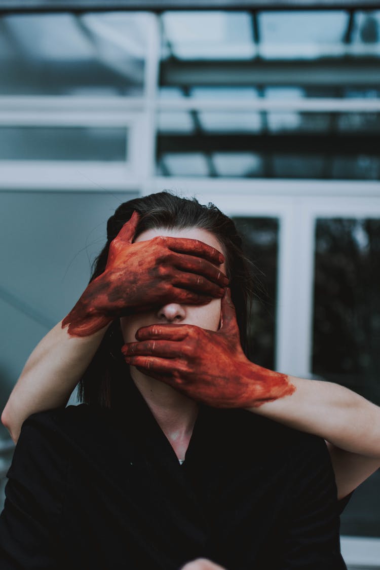 Woman's Face Covered With Bloody Hands