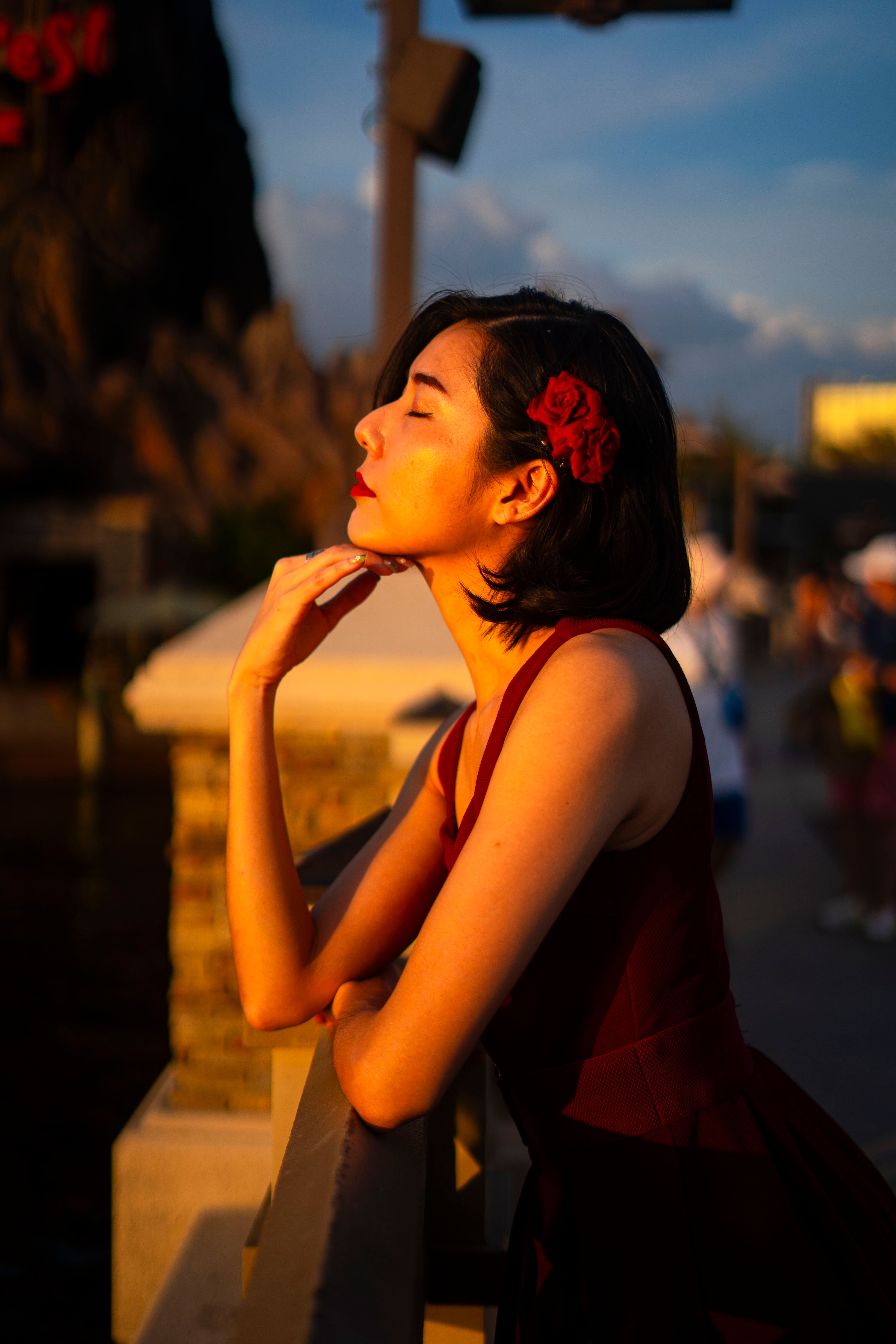 Woman in Red Dress Leaning on Railing at Sunset · Free Stock Photo