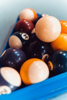 Colorful billiard balls arranged in a triangular rack on a pool table, ready for a game.