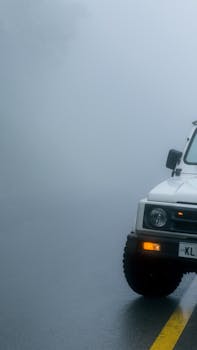 A white off-road vehicle on a misty road, evoking a sense of adventure.