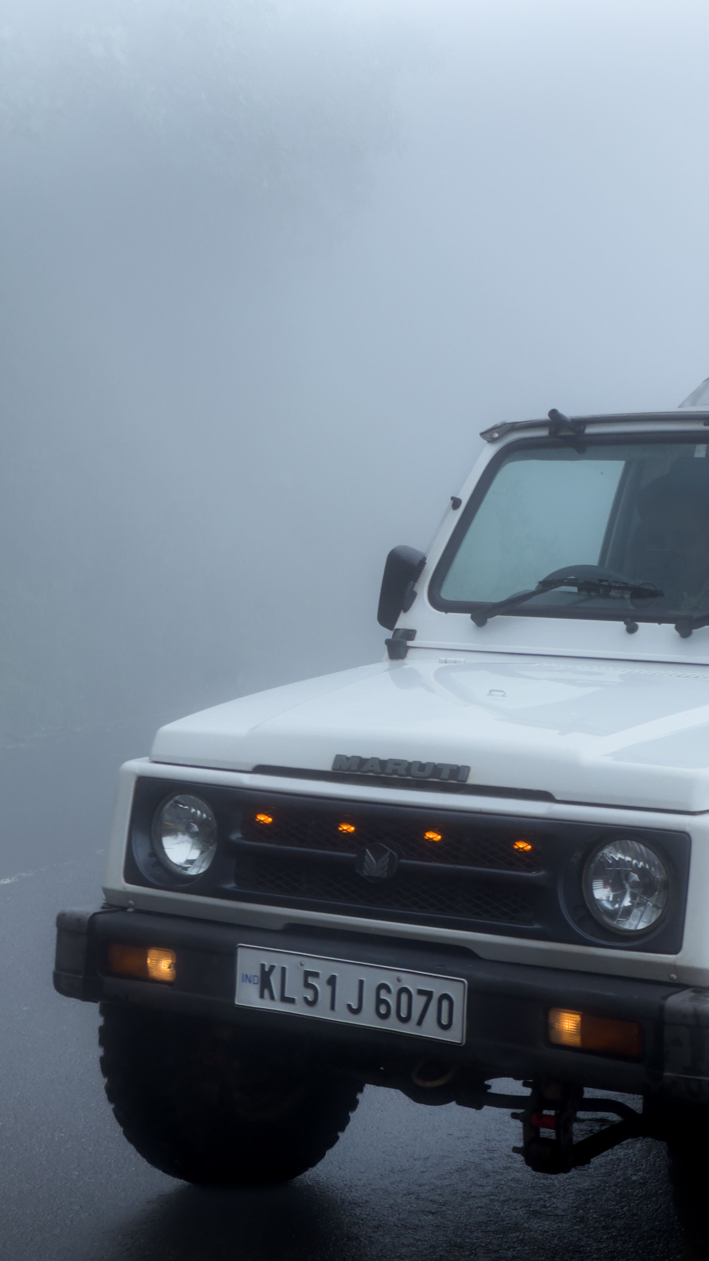 White SUV on a foggy mountain road, creating a mysterious and adventurous vibe.