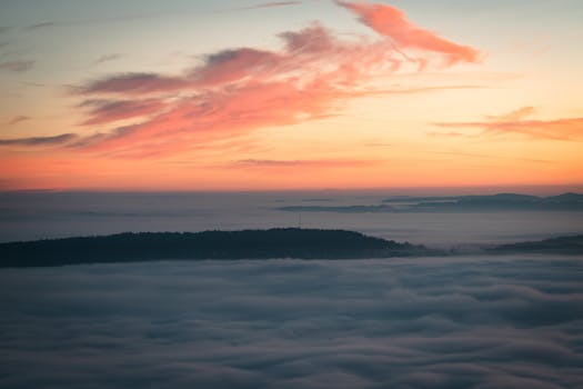 Serene aerial view of a colorful sunrise casting vibrant hues over a mist-covered mountain landscape.