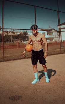 Shirtless man dribbling a basketball on an outdoor court in Istanbul.