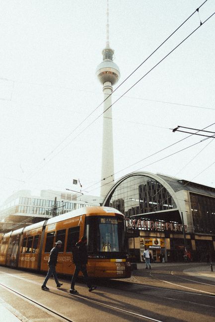 Golden tram passing by the Berlin TV Tower at Alexanderplatz during golden hour.